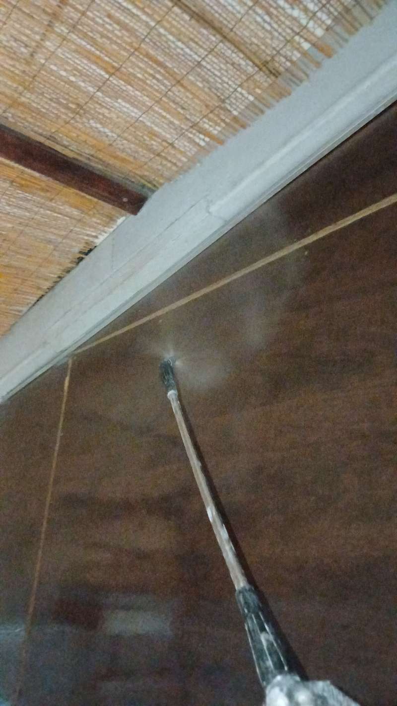 Lanza telescópica aspersando tratamiento sobre vigas y cielo raso de madera