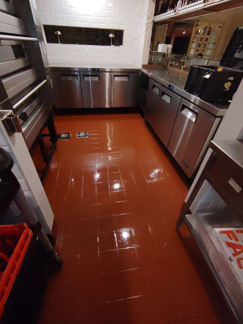 Cocina comercial limpia con piso reluciente y equipos de refrigeración tras el servicio de EcoPlagas